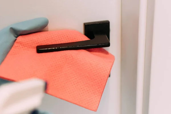 Cropped view of woman cleaning door handle with rag and spray bottle during quarantine — Stock Photo