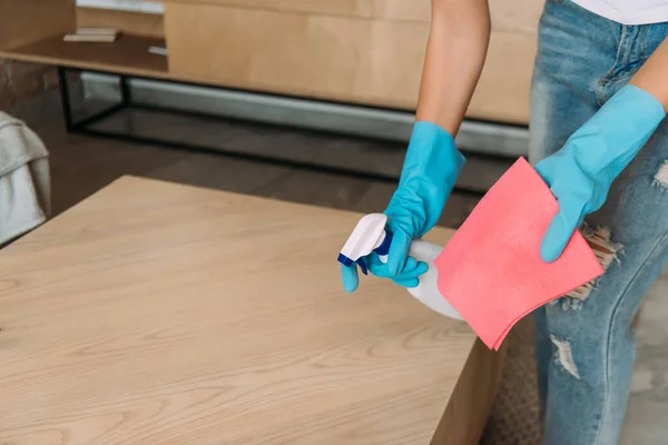 Vue recadrée de la jeune fille dans des gants en caoutchouc table de nettoyage avec chiffon et pulvérisation antiseptique pendant la quarantaine — Photo de stock