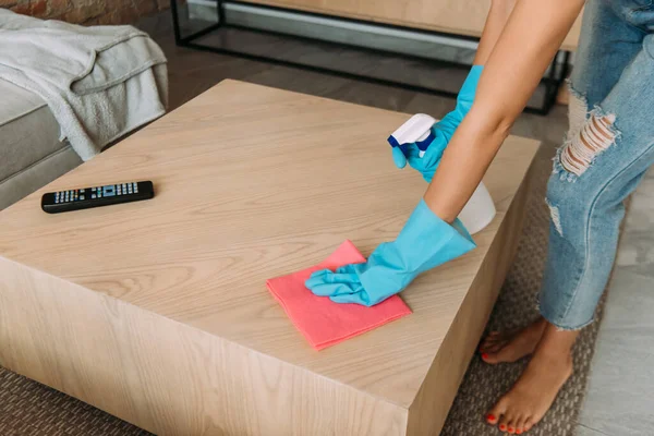 Cropped view of woman in rubber gloves cleaning table with rag and spray bottle during quarantine — Stock Photo