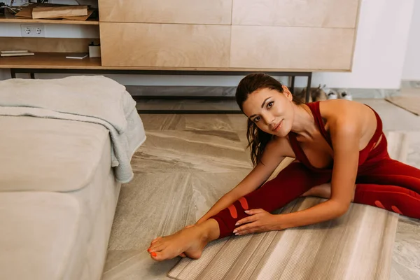 Beautiful smiling girl stretching on yoga mat at home on quarantine — Stock Photo