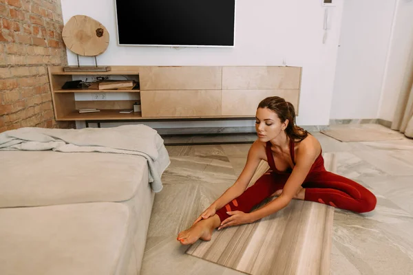 Atractiva chica estiramiento en yoga mat en casa en cuarentena - foto de stock