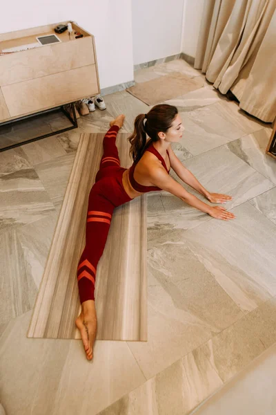 Jolie fille assise en ficelle sur tapis de yoga à la maison pendant l'isolement personnel — Photo de stock