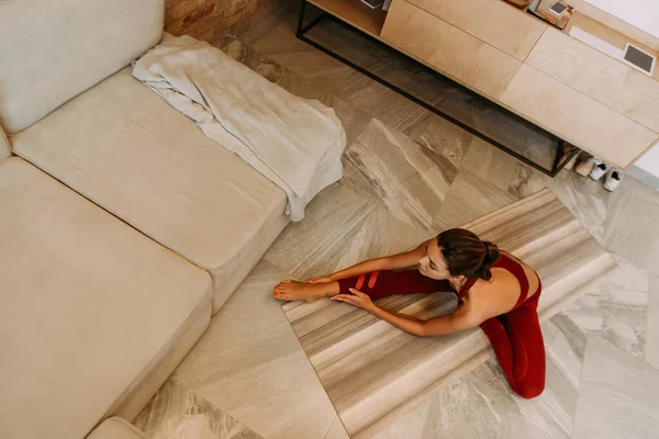 Beautiful woman stretching on yoga mat at home on quarantine, overhead view — Stock Photo