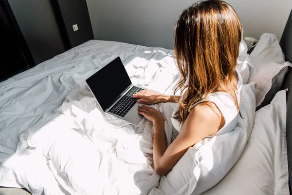 Женщина-фрилансер работает на ноутбуке с чистым экраном во время самоизоляции в постели — стоковое фото