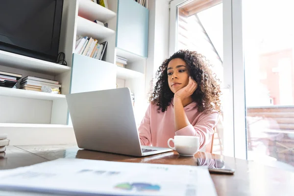 Selective focus of displeased african american freelancer looking at laptop at home — Stock Photo