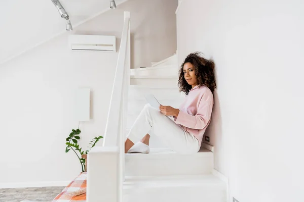 Африканский американский фрилансер сидит на лестнице с ноутбуком — стоковое фото