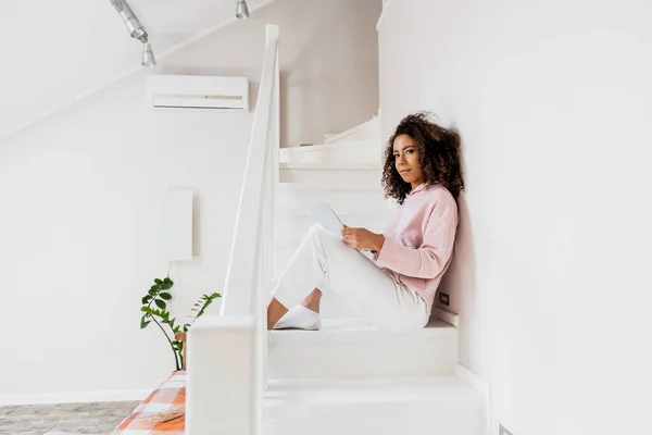 Freelancer afro-americano sentado em escadas com laptop — Fotografia de Stock