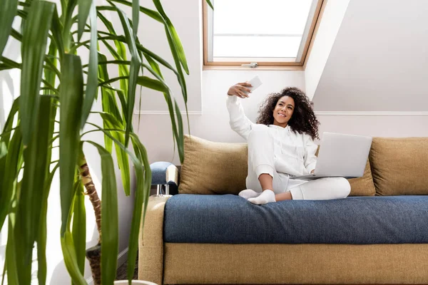 Selective focus of happy young african american freelancer taking selfie near laptop — Stock Photo