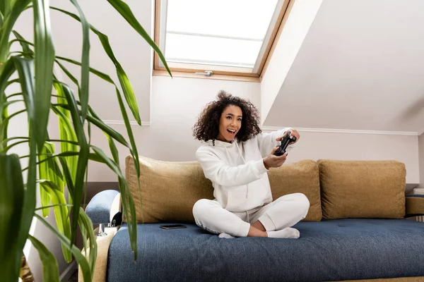 KYIV, UKRAINE - APRIL 15, 2020: selective focus of excited african american girl playing video game at home — Stock Photo