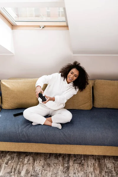 KYIV, UCRÂNIA - 15 de abril de 2020: menina americana africana alegre jogando videogame em casa — Fotografia de Stock