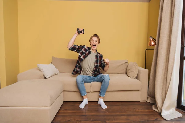 KYIV, UKRAINE - APRIL 24, 2020: excited man holding joystick while playing video game in living room — Stock Photo