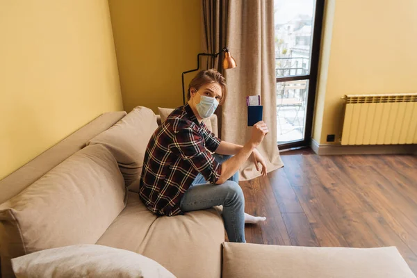 Mann mit medizinischer Maske hält Reisepass mit Flugticket, Ende der Quarantäne — Stockfoto