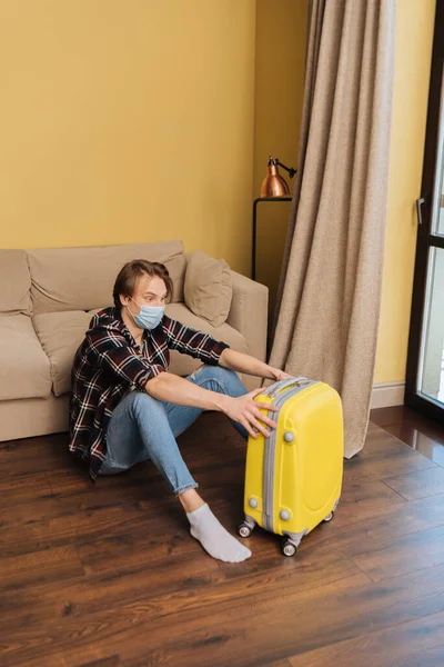 Man in medical mask sitting on floor near baggage, end of quarantine concept — Stock Photo