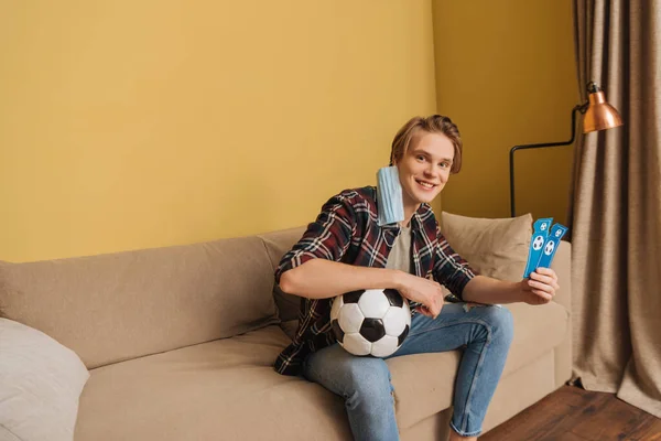 Glücklicher Mann in medizinischer Maske mit Fußball- und Sportspielkarten, Ende der Quarantäne — Stockfoto