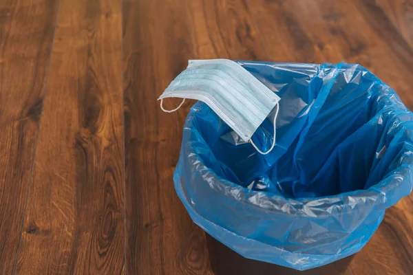 Masque médical bleu dans une poubelle avec sac poubelle, concept de fin de quarantaine — Photo de stock