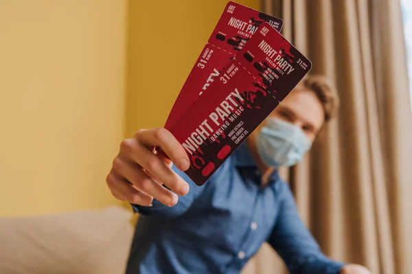 Selective focus of man in medical mask holding night party tickets, end of quarantine concept — Stock Photo