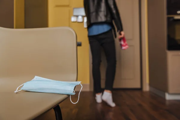 Селективный фокус медицинской маски на столе рядом с человеком, держащим ночные билеты на вечеринку, конец карантинной концепции — стоковое фото