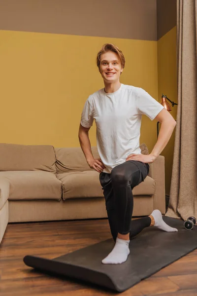 Jeune homme avec les mains sur les hanches faisant de l'exercice sur tapis de fitness, concept de fin de quarantaine — Photo de stock