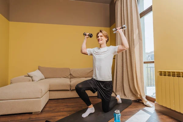 Happy young man exercising with dumbbells in living room, end of quarantine concept — Stock Photo