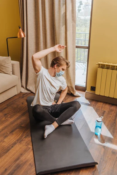 Desportista em máscaras médicas exercício no tapete de fitness — Fotografia de Stock