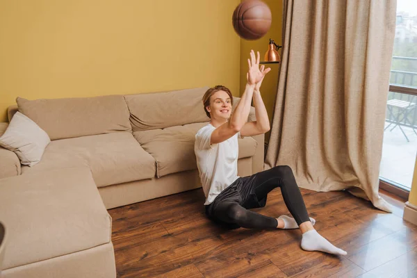 Happy man throwing in air football while sitting on floor, end of quarantine concept — Stock Photo