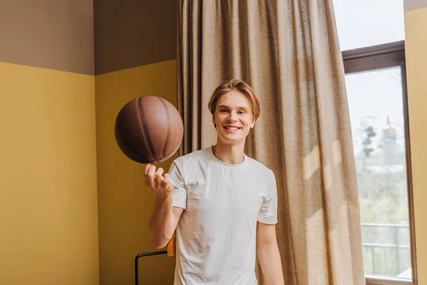 Enfoque selectivo del hombre feliz mirando baloncesto en casa, fin del concepto de cuarentena - foto de stock