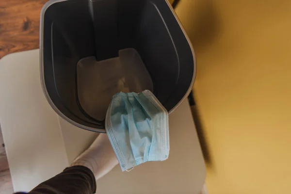 Vista superior del hombre cerca de la máscara médica en el bote de basura, fin del concepto de cuarentena - foto de stock