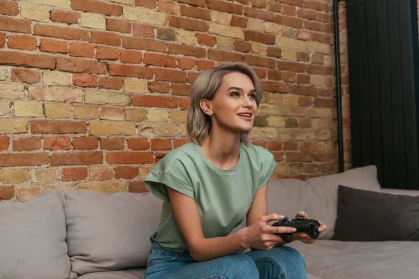 KYIV, UKRAINE - APRIL 30, 2020: excited girl playing video game with joystick at home — Stock Photo