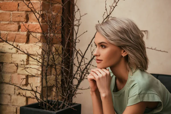 Beautiful, dreamy woman holding hands near chin and looking away — Stock Photo