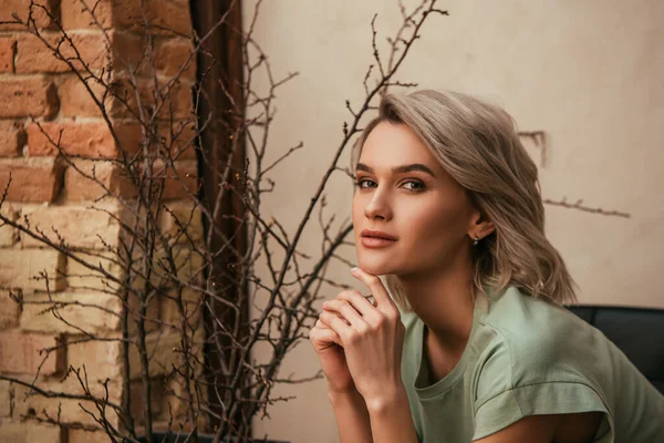 Attractive, dreamy woman holding hands near chin and looking at camera — Stock Photo