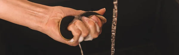 Обрізаний вид жіночої руки з мокрою мильною губкою біля води ізольовано на чорному, горизонтальному зображенні — стокове фото