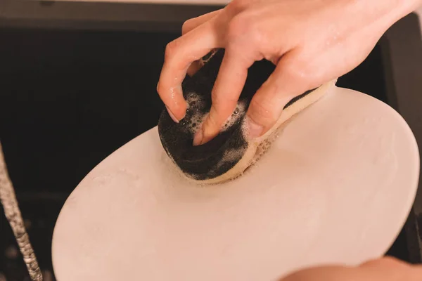 Cropped view of woman cleaning white pate with sponge — Stock Photo