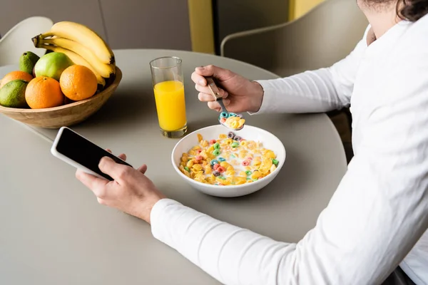 Abgeschnittene Ansicht eines Mannes, der beim Frühstück Smartphone mit leerem Bildschirm hält — Stockfoto