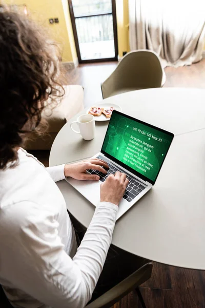 Vista ad alto angolo di freelance con computer portatile con sito web medico vicino a tazza di caffè e piatto con toast — Foto stock