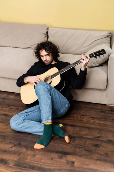 Charmant homme jouant de la guitare acoustique sur le sol dans le salon — Photo de stock