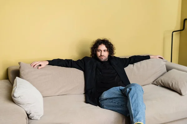 Handsome man sitting on couch in living room — Stock Photo