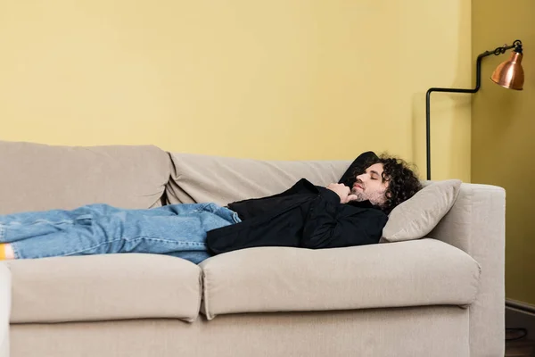Vista lateral do homem deitado no sofá na sala de estar — Fotografia de Stock