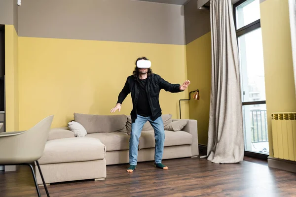Людина у гарнітурі віртуальної реальності стоїть у вітальні — стокове фото