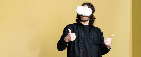 Panoramic shot of man in vr headset showing like gesture at home — Stock Photo