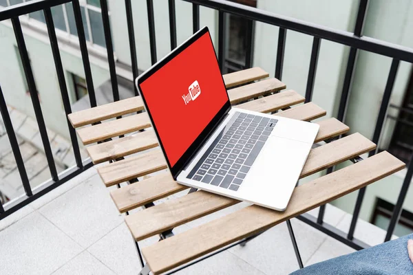 KYIV, UKRAINE - APRIL 25, 2020: Cropped view of laptop with youtube website and man sitting on balcony — Stock Photo