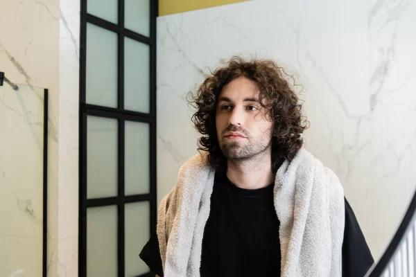 Чоловік з рушником на плечах дивиться на дзеркало у ванній — стокове фото