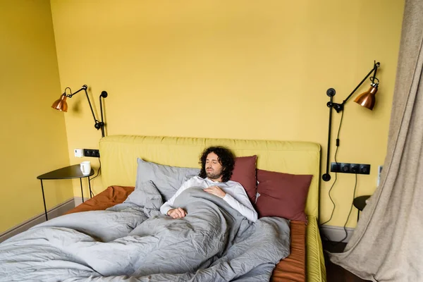 Curly man sleeping in bed at home — Stock Photo