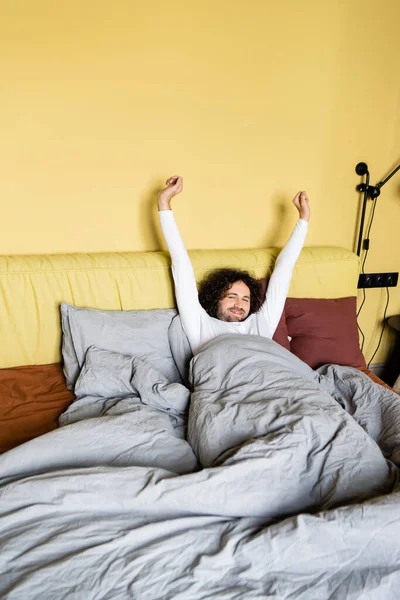 Smiling man stretching while lying in bed — Stock Photo