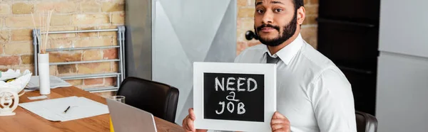 Tiro panorâmico de homem americano africano barbudo segurando quadro-negro com necessidade de um trabalho lettering — Fotografia de Stock