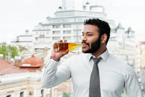 Homme afro-américain barbu en masque médical boire de la bière à l'extérieur — Photo de stock