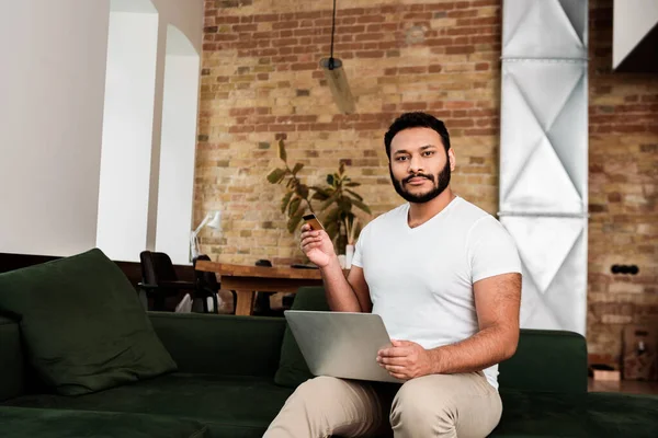 Bearded african american man holding credit card near laptop — Stock Photo