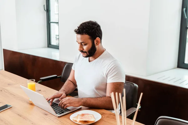 Bearded african american freelancer working from home near breakfast — Stock Photo