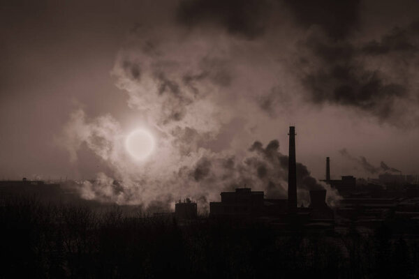 Smoking chimneys of a factory at dawn on a black and white photo