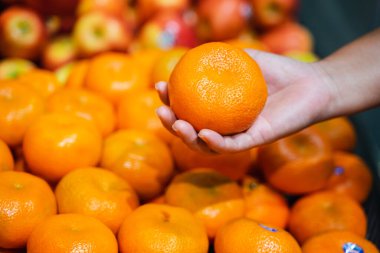 Kadın eli süpermarkette portakal seçiyor.