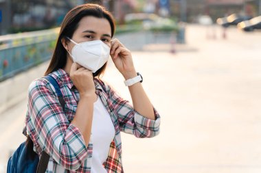 Çevre kirliliğini ve virüsü korumak için N95 maskesi takan Asyalı kadın. Covid-19 Coronavirus ve Hava kirliliği pm2.5 kavramı.